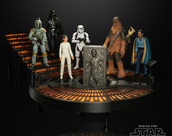 Puede incluir: Un conjunto de figuras de acción de Star Wars The Black Series con personajes como Darth Vader, Boba Fett y Chewbacca. Las figuras se exhiben en una plataforma circular con iluminación naranja y un Han Solo en carbonita. El set está a escala para Star Wars.