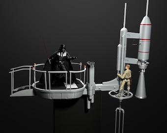 Puede incluir: Figuras de acción de Darth Vader y Luke Skywalker en un set de juego de Star Wars. El set de juego incluye una plataforma con una barandilla y una estructura similar a un cohete con una plataforma de aterrizaje.