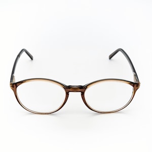 May include: Oval-shaped eyeglasses with a brown frame and black temples. The lenses are clear, and the glasses are set against a white background. The frame has a translucent quality.