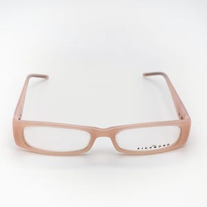 May include: Pale pink rectangular eyeglasses with clear lenses. The frames have a subtle, matte finish. The brand name "RICHMOND" is printed on the lower right lens. The glasses are set against a white background.