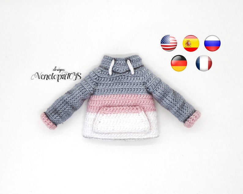 May include: A gray, pink, and white striped crocheted hoodie with a white drawstring. The hoodie has a pocket on the front.