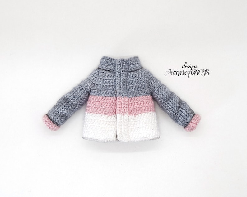 May include: A gray, pink, and white crocheted jacket with a zipper closure. The jacket has a striped pattern and is made with a soft yarn.