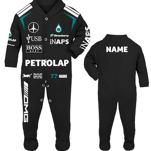 May include: A black long-sleeved baby romper featuring white and teal racing-inspired graphics, including the text PETROLAP, BOSS BABY, USB, iNAPS, and NAME. The design includes a Mercedes-style logo, a cat silhouette, and a British flag graphic.