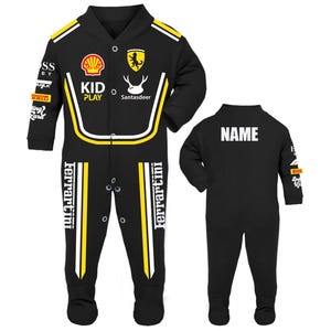 K&ouml;nnte beinhalten: Schwarzer Baby-Overall mit gelben und wei&szlig;en Akzenten, versehen mit Logos und Texten zum Thema Rennsport. Auf der Vorderseite sind die Marken "KID PLAY" und "Ferrari" zu sehen. Auf der R&uuml;ckseite des Overalls steht das Wort "NAME" in Wei&szlig;.