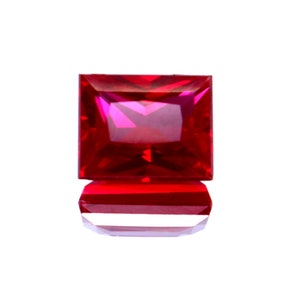 Può includere: Una pietra preziosa quadrata di colore rosso scuro con taglio a faccette.