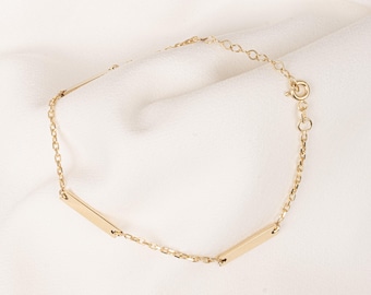 Op de afbeelding: Een gouden kettingarmband met twee rechthoekige staafcharms.