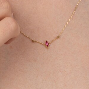 Op de afbeelding: Een delicate gouden ketting met een enkele hanger in de vorm van een marquise-slijpsel van robijn.