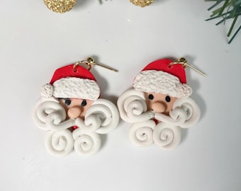 May include: A pair of festive Santa Claus earrings. Each earring features a red hat with white trim, a rosy face, and a white curly beard and mustache. The earrings are made of polymer clay and have gold-colored ear wires. Perfect for Christmas.