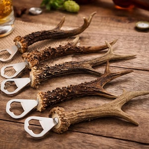 Può includere: Cinque apribottiglie a forma di corno con teste apribottiglie in metallo argentato sono disposti su una superficie di legno. I corni sono marroni e beige, con un aspetto naturale e rustico. Un bicchiere di birra e tappi di bottiglia sono sullo sfondo.