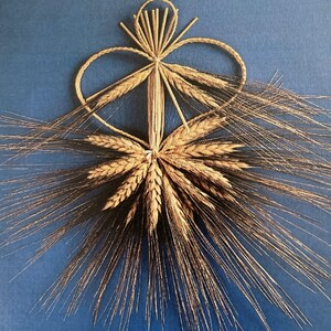 May include: A golden wheat sheaf tied into a heart shape against a blue background.