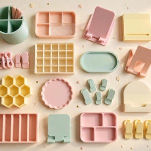 May include: A collection of pastel-coloured desk organisers and accessories including a pen holder, divided trays, phone stands, a honeycomb-shaped container, a scalloped dish, and various clips in shades of mint green, soft pink, and pale yellow.
