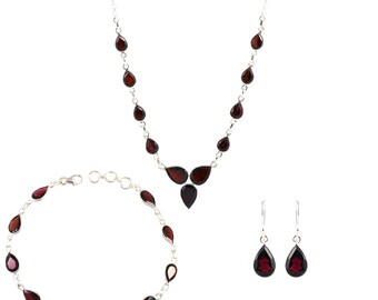 May include: A silver necklace, bracelet and earrings set with teardrop-shaped red gemstones.