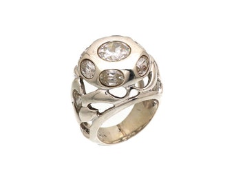 May include: A silver ring with a large, round, clear stone surrounded by smaller clear stones. The ring has a delicate, intricate design.