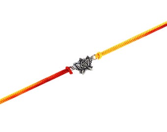 May include: A silver-colored lotus flower charm bracelet with a red and yellow cord. The bracelet features a detailed floral design and is set against a white background. The cord is a vibrant gradient of red to yellow.