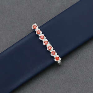 May include: A silver bracelet with a row of red heart-shaped stones.