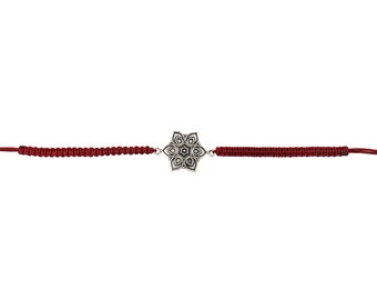 May include: A silver-colored flower charm bracelet with a burgundy cord. The charm is a detailed, six-petal design. The bracelet is a simple, elegant piece of jewelry.