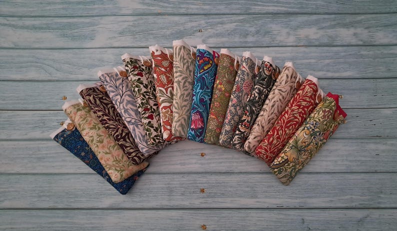 May include: A collection of fabric cases, each with a unique floral or botanical pattern in various colors. The cases are arranged in a semi-circle, showcasing a variety of designs and textures. Each case has a white top and a button closure.
