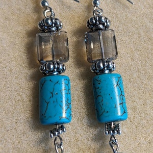May include: A pair of dangle earrings with turquoise and clear crystal beads. The earrings have silver-toned metal accents and hooks.