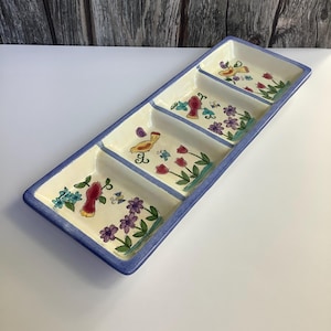 May include: Rectangular ceramic serving dish with four compartments. The dish has a cream-colored interior with a blue border. Each compartment features a different hand-painted design of birds, flowers, and foliage in red, purple, and yellow.