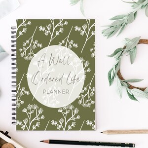 May include: A green spiral bound planner with a white floral pattern and the text "A Well Ordered Life Planner" in a circle.