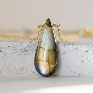 May include: A teardrop-shaped labradorite gemstone pendant necklace with a gold chain.