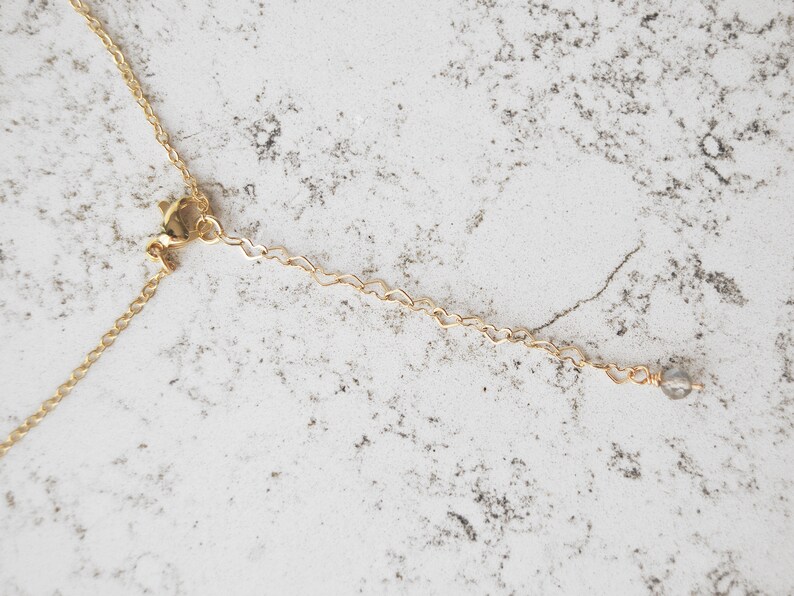 May include: A gold chain necklace with a lobster clasp and a small clear crystal at the end.
