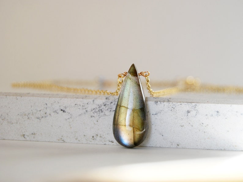 May include: A teardrop-shaped labradorite gemstone pendant necklace with a gold chain.