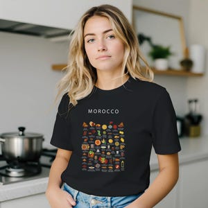 T-shirt featuring a colorful illustration of traditional Moroccan foods, including a steaming tagine, fluffy couscous, bowl of harira soup, fresh mint tea, and assorted sweet pastries, styled in a vibrant street-food design