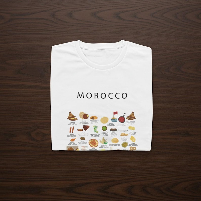 T-shirt featuring a colorful illustration of traditional Moroccan foods, including a steaming tagine, fluffy couscous, bowl of harira soup, fresh mint tea, and assorted sweet pastries, styled in a vibrant street-food design