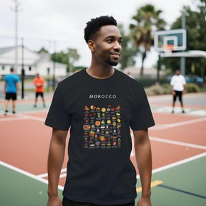 T-shirt featuring a colorful illustration of traditional Moroccan foods, including a steaming tagine, fluffy couscous, bowl of harira soup, fresh mint tea, and assorted sweet pastries, styled in a vibrant street-food design