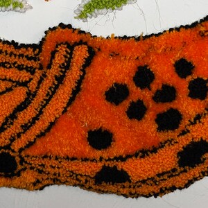 May include: Orange and black crocheted rug shaped like a clog shoe.