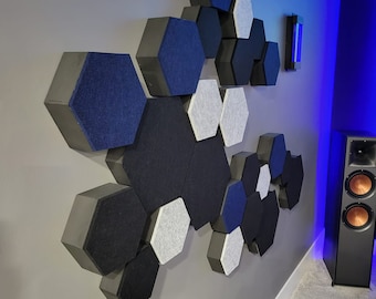 Puede incluir: Una pared cubierta con paneles acústicos en varios tonos de gris y azul. Los paneles son hexagonales y están dispuestos en un patrón aleatorio. La pared está pintada de un color gris claro.
