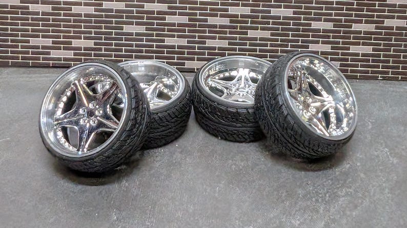 Pode incluir: Quatro rodas de liga leve cromadas com pneus pretos. As rodas t&ecirc;m um design em forma de estrela no centro e um acabamento polido. Os pneus t&ecirc;m um padr&atilde;o de piso.