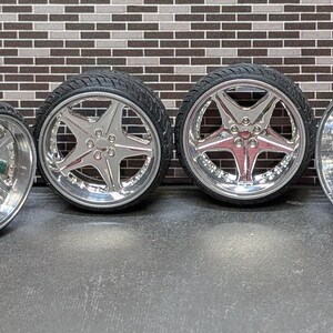 Pode incluir: Quatro rodas cromadas para carro com pneus pretos. As rodas t&ecirc;m um design em forma de estrela de cinco pontas. Os pneus t&ecirc;m um padr&atilde;o texturizado e ranhurado. As rodas s&atilde;o exibidas contra uma parede de tijolos.