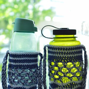 May include: Two water bottles with crochet bottle holders. One bottle has a green lid, the other a black lid. The holders are blue and white, with a braided strap. The bottles are on a white surface, with a blurred green background.