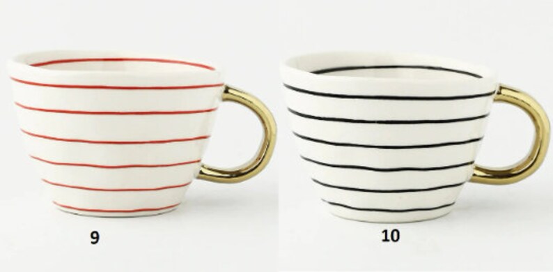 May include: Two ceramic mugs with gold handles. The mug on the left has red stripes and the mug on the right has black stripes. Both mugs are on a white background. 9 and 10 are written below the mugs.
