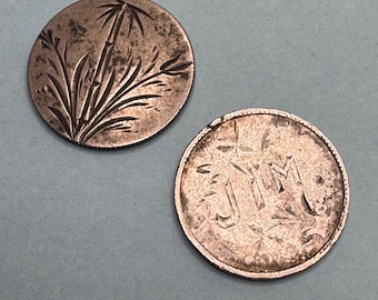 May include: Two antique copper coins. One coin features an etched bamboo design. The other coin has the initials "J M" etched into the surface. Both coins have a worn, aged appearance.