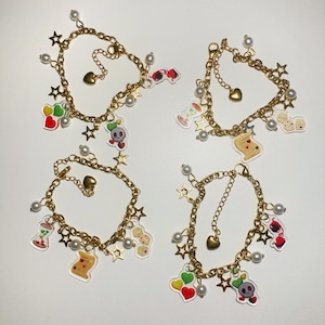 May include: Four gold charm bracelets with white pearl beads and various charms, including hearts, stars, playing cards, and skulls.