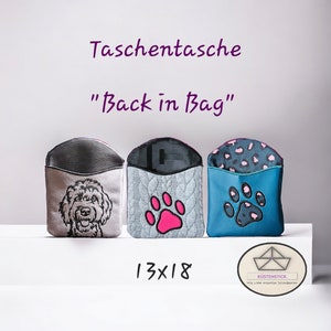 Op de afbeelding: Drie kleine ritszakjes met verschillende ontwerpen. Het zakje links heeft een grijze achtergrond met een witte geborduurde hond. Het middelste zakje heeft een lichtblauwe achtergrond met een roze pootprint. Het zakje rechts heeft een teal achtergrond met een zwarte pootprint en een roze luipaardprint voering. De zakjes zijn gelabeld "Taschentache" en "Back in Bag" en "13x18".