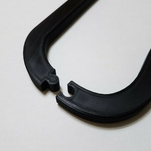 May include: A black plastic U-shaped hanger with a textured surface.