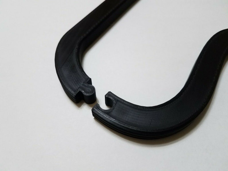 May include: A black plastic U-shaped hanger with a textured surface.