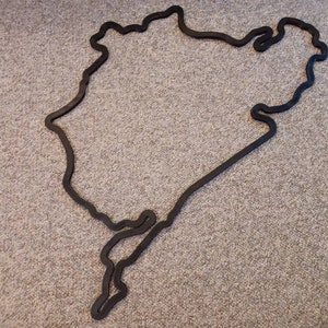 May include: Black outline of a race track on a gray carpet.