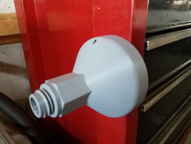 May include: A grey plastic 3D printed adapter with a threaded end and a round, flat base. The adapter is mounted to a red surface.