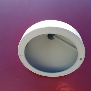 May include: A white plastic round light fitting with a hole in the centre. The fitting is mounted on a red surface.