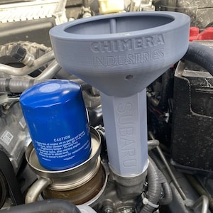 May include: A gray 3D printed oil funnel with the text "CHIMERA INDUSTRIES" and "SUBARU" printed on it. The funnel is being used to pour oil into a car engine.