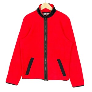 May include: A red fleece jacket with a black zipper and black accents on the pockets and collar. The word "CAMP" is printed in white on the collar. The jacket is hanging on a wooden hanger.