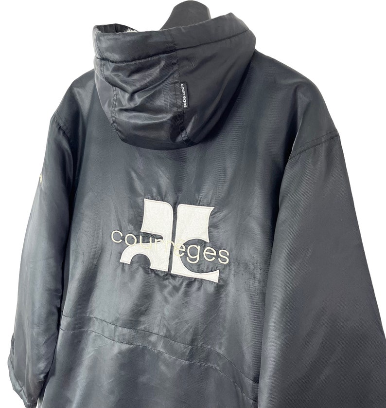 May include: Black hooded jacket with a white "Courreges" logo on the back. The jacket has a zipper closure and a drawstring hood.