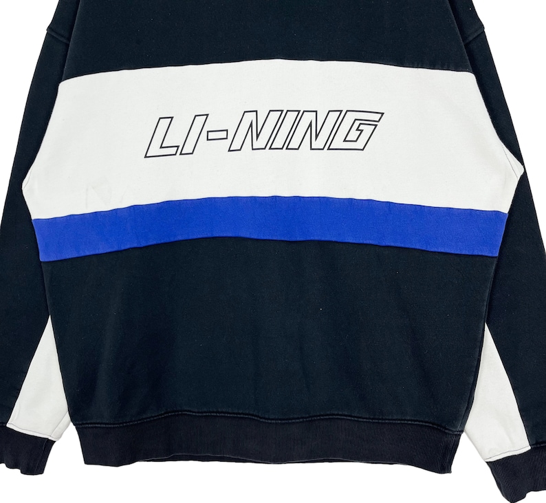 May include: Black and white striped sweatshirt with a blue stripe and the text "LI-NING" in black.
