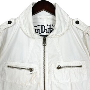 K&ouml;nnte beinhalten: Wei&szlig;e Baumwolljacke mit Rei&szlig;verschluss und mehreren Taschen. Die Jacke hat ein "Von Dutch" Logo auf der Innenseite des Kragens.