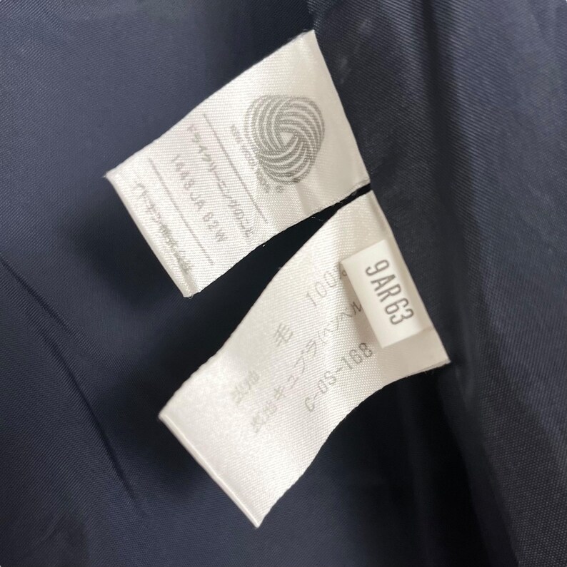May include: White care label with the text "Dry Clean Only" and "1448 JA 82W" in Japanese. A second white label with the text "9AR 63", "100% Wool", "C-OS-168" in Japanese.